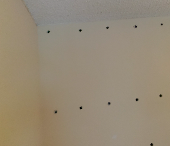 White ceiling and wall with holes drilled in. 