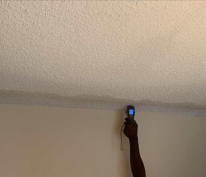 White wall with discoloration on the ceiling causing it to become dark. 