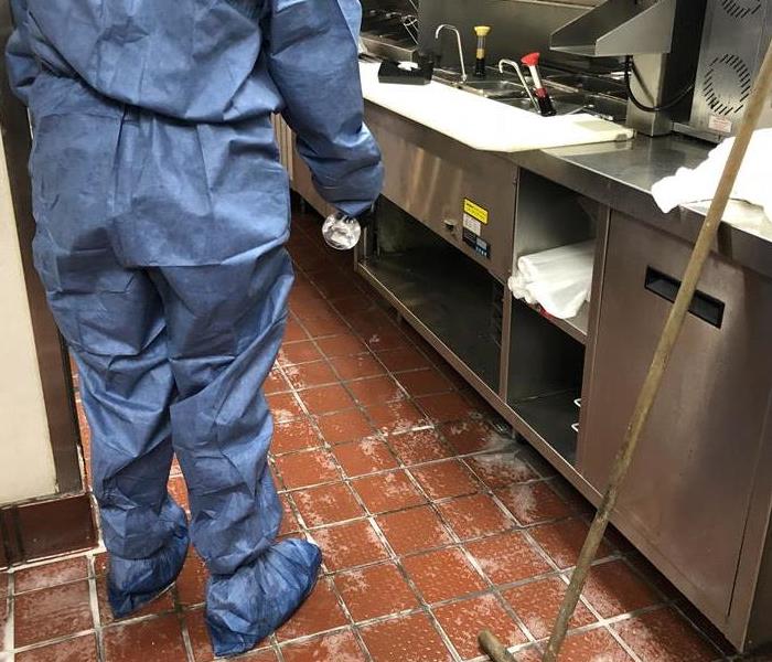 technician in protective gear cleaning a tile floor. 