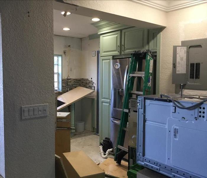 Kitchen with green cabinets and appliances pulled out.