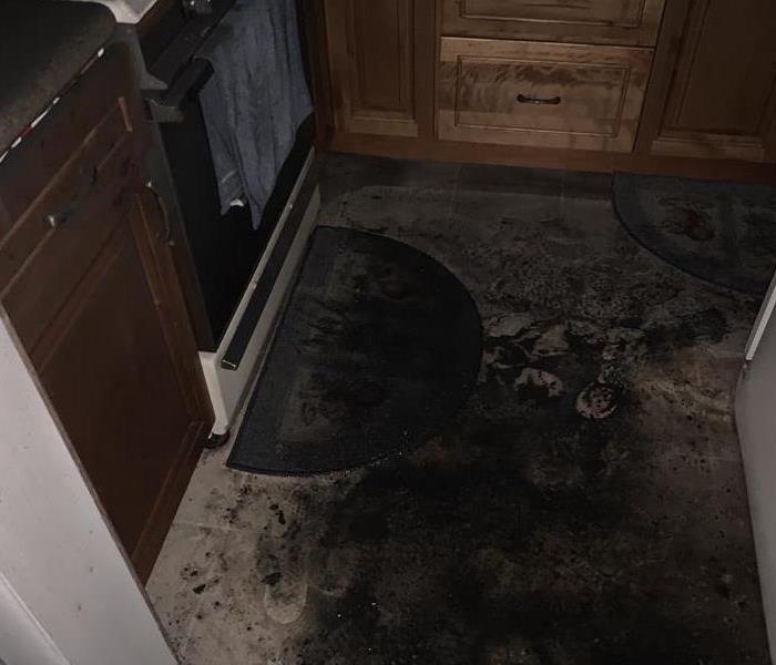 Kitchen floor covered in black soot. 
