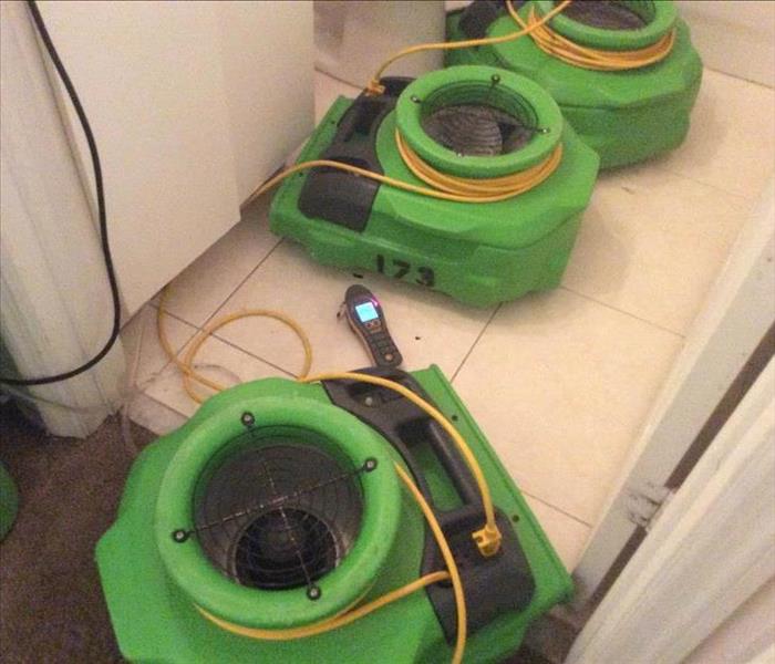 Three green air movers on a white tile floor. 