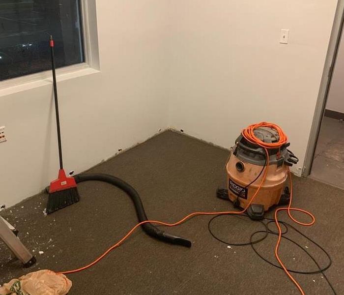 Water vacuum on the carpet flooring with orange cords. 
