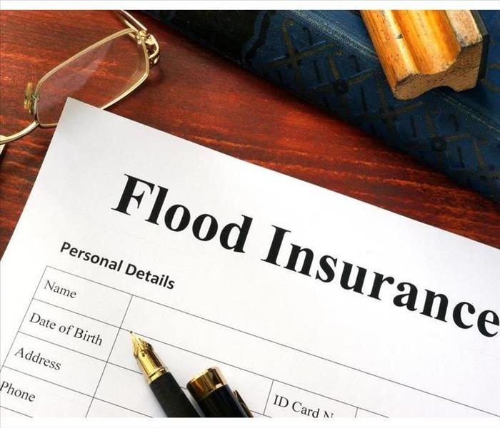 Flood insurance form on a table with a pen and glasses on a table