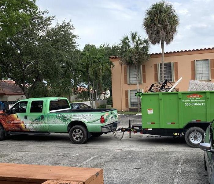 SERVPRO green truck toting around a dumpster full of moldy material.